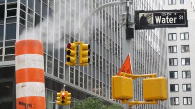 New York Su Sokağı 'nda buhar sızıntısı, turuncu buhar borusu yığını. Pipo dumanı. Con Edisons Buhar Operasyonları Sistemi, Manhattan şehir merkezi finans bölgesi mimarisi. Trafik ışığı