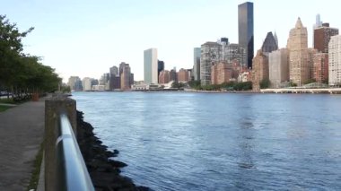New York şehri kıyısı silueti, Manhattan şehir merkezi binaları, nehir kıyısındaki gökdelenler, doğu nehri suyu. Roosevelt Adası 'ndan deniz kenarı manzarası. Birleşik Devletler mimarisi ve gayrimenkul.