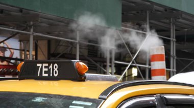 New York City, ABD - 8 Eylül 2023: Buhar caddeye buhar püskürtüyor, turuncu tüp yığını. Sıcak duman piposu. Con Edisons Buhar Operasyonları Sistemi, Manhattan 5. Cadde. Sarı taksi, iskele.