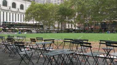 New York, ABD - 13 Eylül 2023: Manhattan şehir merkezi Bryant Park, 42 sokak ve 5. Cadde. ABD simgesi. Yeşillikte boş sandalye ve masa. Yeşil çimen.