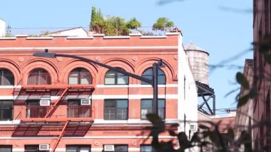 New York City Manhattan mimarisi. Şehir dışındaki konutlar. ABD 'de gayrimenkul. Kırmızı tuğla cephe. Yangın çıkışı, acil merdiven çıkışı. Çatıdaki su kulesi, çatıdaki tank..