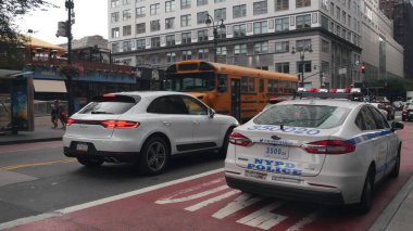New York, ABD - 29 Ağustos 2023: Manhattan 34 caddesindeki Sarı Okul Otobüsü, 8 bulvarındaki okul otobüsü ve polis arabası. Çocuk eğitimi, yol ulaşımı, NYPD ABD. Amerikan okul servisi.