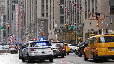 New York, ABD - 10 Eylül 2023: Polis devriye arabası, Radio City Music Hall. ABD NYPD 911, Manhattan Midtown Caddesi. Amerikan polisi araba siren ışığı, 6. Cadde. Şehir trafiği. Sarı taksi.