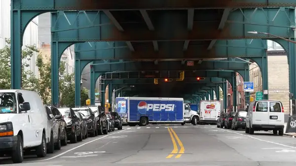 New York, Birleşik Devletler - 31 Ağustos 2023 Pepsi kamyonu, sokağın üstündeki metro yükseltilmiş. Yolun üzerindeki Metropolitan Köprüsü, Queens. Long Island metro hattı. Metalik demiryolu altında arabalar. NYC şehir hayatı.