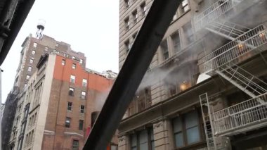 New York caddesinde buhar sızıntısı, turuncu buhar borusu yığını. Pipo dumanı. Con Edisons Buhar Operasyonları Sistemi, 5. Cadde, Manhattan Midtown. Yangın merdiveni, çatı kulesi tankı.