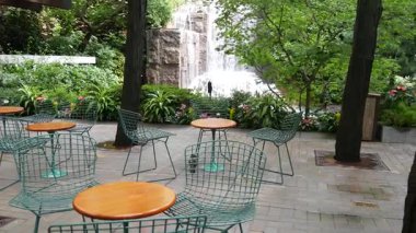 New York şehri hayatı, şehir parkı, Greenacre Park şelalesi. Amerikan Manhattan Midtown, ABD. Eğlence bölgesi yaz çiçekleri, ağaçlar yeşillik. Boş sandalyeler ve masalar. New York 'ta yeşil vaha.