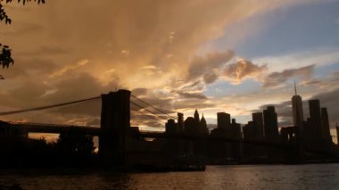 Brooklyn Köprüsü ve New York City Manhattan şehir merkezi silueti, finans bölgesi şehir manzarası. Birleşik Devletler Dünya Ticaret Merkezi gökdeleni. Waterfront Pebble Sahili, Dumbo, ABD. Dramatik gün batımı bulutlu gökyüzü