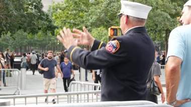 New York City, ABD - 11 Eylül 2023: İtfaiyeciler Vatanseverlik Günü 'nü kutladı. 911 Anma Havuzu 'nun yanında bir polis memuru var. İtfaiye yaşlı itfaiyeci Manhattan Downtown, ABD 'de insanlarla konuşuyor.