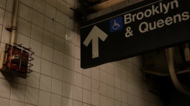 New York metro istasyonu içi, mesaj işareti. Manhattan yeraltı metropolü. Birleşik Devletler metro nakliye navigasyonu. Bilgi levhası kamu yolcu tren yolu. Queens ve Brooklyn yönü.
