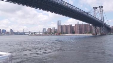 Feribottan New York City silueti. Manhattan şehir merkezindeki gökdelenler feribottan görünüyor. Doğu nehri kıyısı manzarası, nehir kıyısındaki binalar ABD suları yakınında. Williamsburg Köprüsü