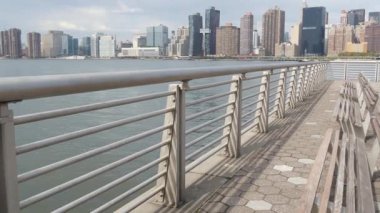 New York şehri kıyısı silueti, Manhattan şehir merkezi binaları, nehir kıyısındaki gökdelenler, doğu nehri suyu. Waterside City, Gantry Plaza Park, Long Island, Queens, ABD. Nehir kenarındaki bank.