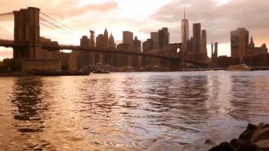 Brooklyn Köprüsü ve New York City Manhattan şehir merkezi silueti, finans bölgesi şehir manzarası. Birleşik Devletler Dünya Ticaret Merkezi gökdeleni. Waterfront Pebble Sahili, Dumbo, ABD. Dramatik gün batımı bulutlu gökyüzü