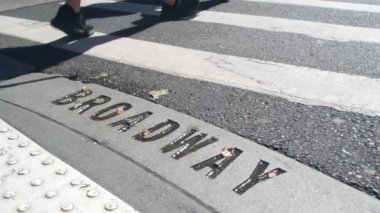Broadway sokak tabelası, yaya zebra kavşağındaki insanlar. New York City Manhattan kavşağı. Yaya geçidinde asfalt, kavşaktaki gölgeler. Trafik levhası, Birleşik Devletler