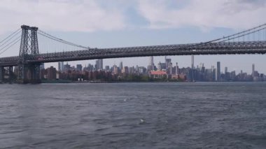 Feribottan New York City silueti. Manhattan şehir merkezindeki gökdelenler feribottan görünüyor. Doğu nehri kıyısı manzarası, nehir kıyısındaki binalar ABD suları yakınında. Williamsburg Köprüsü