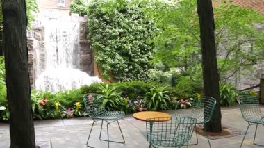 New York şehri hayatı, şehir parkı, Greenacre Park şelalesi. Amerikan Manhattan Midtown, ABD. Eğlence bölgesi yaz çiçekleri, ağaçlar yeşillik. Boş sandalyeler ve masalar. New York 'ta yeşil vaha.