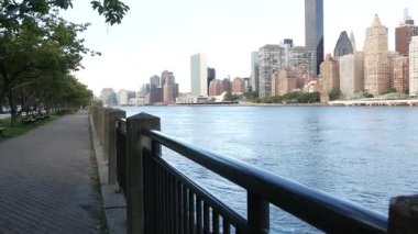 New York şehri kıyısı silueti, Manhattan şehir merkezi binaları, nehir kıyısındaki gökdelenler, doğu nehri suyu. Roosevelt Adası 'ndan deniz kenarı manzarası. Birleşik Devletler mimarisi ve gayrimenkul.
