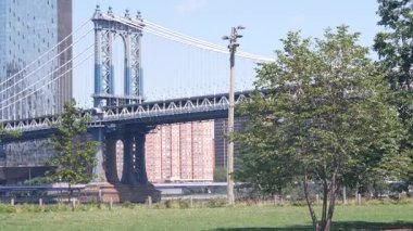 Manhattan Köprüsü 'nden Brooklyn Dumbo' ya. New York 'un sembolü, Amerika' nın seyahat yeri. Birleşik Devletler 'in mimarisi, turizm simgesi. Kablolu yayın köprüsü. Park yeşili, nehir kenarında yeşil çimen pikniği..