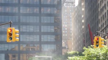 New York caddesinde buhar sızıntısı, buhar borusu yığını. Pipo dumanı. Con Edisons Buhar Operasyonları Sistemi, Manhattan finans bölgesi mimarisi. Sarı trafik ışığı, gökdelen.