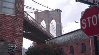 Dumbo 'dan New York City Brooklyn Köprüsü' ne. Kırmızı tuğla duvar, eski tarihi tütün deposu, Market ve Tiyatro. Düşük açı. Amerika Birleşik Devletleri 'ni gezmek, mimarlık. Tek yön ok, dur işareti..