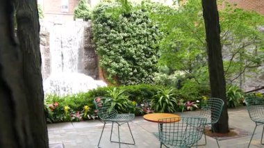 New York şehri hayatı, şehir parkı, Greenacre Park şelalesi. Amerikan Manhattan Midtown, ABD. Eğlence bölgesi yaz çiçekleri, ağaçlar yeşillik. Boş sandalyeler ve masalar. New York 'ta yeşil vaha.