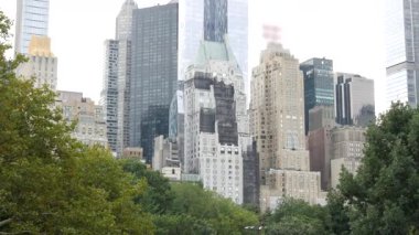 New York Şehri Manhattan Midtown. 5. Cadde 'deki Central Park, ABD. Amerika 'nın simgesi, NYC, ABD' deki şehir parkı. Gökdelen binaları mimarisi, 59 sokak silueti. Yeşil ağaçlar.