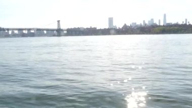 Feribottan New York City silueti. Manhattan şehir merkezindeki gökdelenler feribottan görünüyor. Doğu nehri kıyısı manzarası, nehir kıyısındaki binalar ABD suları yakınında. Williamsburg Köprüsü