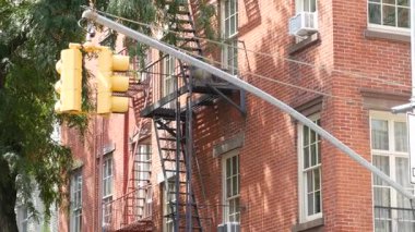 New York caddesi kavşağı, sarı trafik ışığı, ulaşım yolu kavşağı, Birleşik Devletler. Konut mimarisi. New York Emlak, yangın merdivenli kırmızı kahverengi tuğlalı ev. Manhattan.