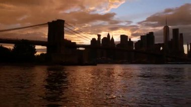 Brooklyn Köprüsü ve New York City Manhattan şehir merkezi silueti, finans bölgesi şehir manzarası. Birleşik Devletler Dünya Ticaret Merkezi gökdeleni. Waterfront Pebble Sahili, Dumbo, ABD. Dramatik gün batımı bulutlu gökyüzü
