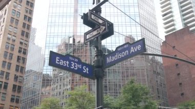 New York City kavşağı, Manhattan köşesi, Madison Bulvarı, sokak kavşağı tabelası. Midtown merkez bölgesi mimarisi, Birleşik Devletler. Tek yönlü ok işareti, gökdelenler. Düşük açı.