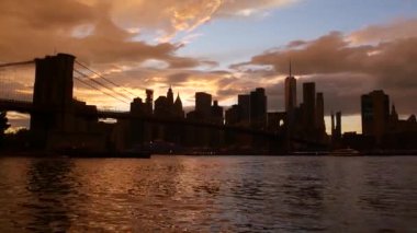 Brooklyn Köprüsü ve New York City Manhattan şehir merkezi silueti, finans bölgesi şehir manzarası. Birleşik Devletler Dünya Ticaret Merkezi gökdeleni. Waterfront Pebble Sahili, Dumbo, ABD. Dramatik gün batımı bulutlu gökyüzü