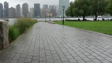 New York şehri kıyısı silueti, Manhattan şehir merkezi binaları, nehir kıyısındaki gökdelenler, doğu nehri suyu. Rıhtım kenti yağmurlu, sisli manzara, Gantry Plaza Park, Long Island, Queens, ABD.