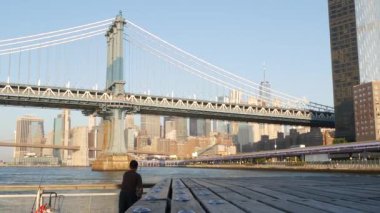 New York, Birleşik Devletler - 7 Eylül 2023: Manhattan Köprüsü. Rıhtım 35 'in yanındaki balıkçı salıncak, şehir merkezindeki deniz kenarı manzarası. Dünya Ticaret Merkezi gökdeleni, insanlar balık tutuyor ve sabah günbatımı.