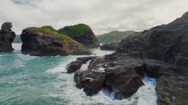 The drone footage captures stunning island peaks at Piha beach, offering a bird's eye view of the rugged and dramatic landscapes