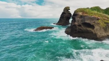 The drone footage captures stunning island peaks at Piha beach, offering a bird's eye view of the rugged and dramatic landscapes