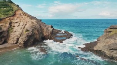 The drone footage captures stunning island peaks at Piha beach, offering a bird's eye view of the rugged and dramatic landscapes