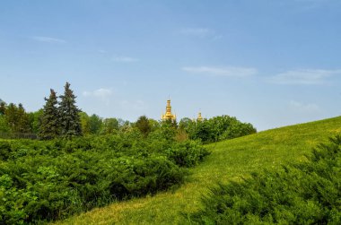 Çalıları olan güzel bir tepe. Uzakta Kiev-Pechersk Lavra 'nın kubbeleri var. Kyiv