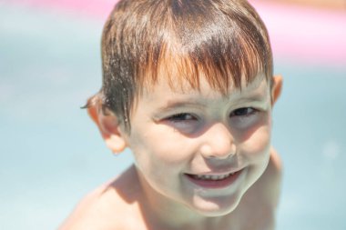 Yazın kameraya bakarken gülümseyen 5 yaşındaki bir çocuğun portresi