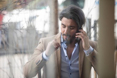 Pencereden sigara içerken çekilmiş yakışıklı bir genç adam.