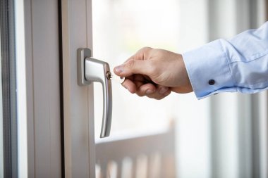 Gündüz vakti balkon kapısını kilitleyen bir elin yakınlaşması