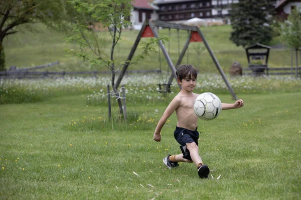 美しい少年は牧草地でサッカーをしている — ストック写真