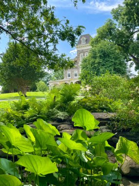 Baltimore, Maryland 'deki Cylburn Arboretum' daki eski güzel malikâne yazın parlak mavi bir kayağın altında bahçelerin yemyeşil yapraklarının arkasında kısmen görülebilir..