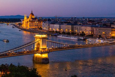 Macaristan 'ın Budapeşte kentindeki Szechenyi Lanchid köprüsü ve Macaristan Parlamento Binası ile Tuna Nehri' nin akşam manzarası