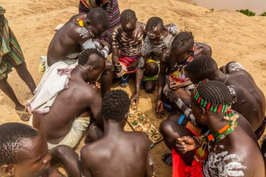KORCHO, ETHIOPIA - 4 Şubat 2020: Karo kabilesinin erkekleri Korcho köyünde mancala (bao) oyunu oynuyorlar