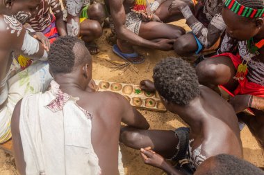 KORCHO, ETHIOPIA - 4 Şubat 2020: Karo kabilesinin erkekleri Korcho köyünde mancala (bao) oyunu oynuyorlar