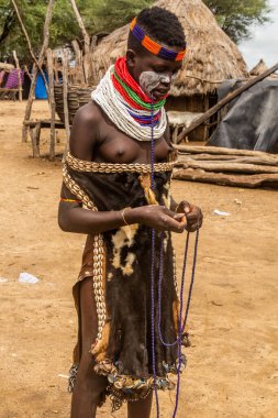 KORCHO, ETHIOPIA - 4 Şubat 2020: Karo kabile kızı, Etiyopya 'daki Korcho köyünde boncuk kolye yapıyor.