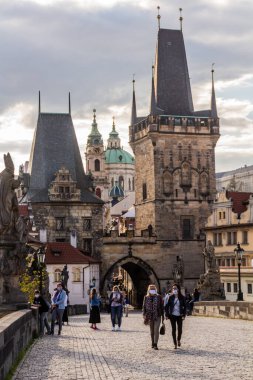 PRAG, CZECHIA - 27 Nisan 2020: Maskeli adamlar Çek Cumhuriyeti 'ndeki COVID-19 karantinası sırasında Prag' daki Charles Köprüsü 'nden geçiyorlar.