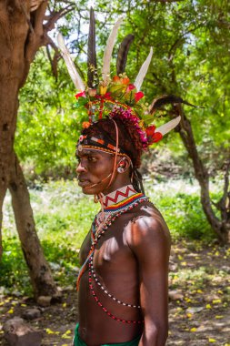 GÜNEY HORR, KENYA - 12 Şubat 2020: Samburu kabilesi delikanlısı sünnet töreninden sonra devekuşu tüylerinden yapılmış renkli bir başlık takıyor. Kenya 'nın Güney Horr köyünde çekildi.