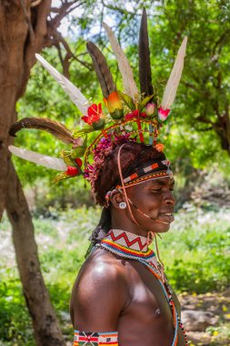 GÜNEY HORR, KENYA - 12 Şubat 2020: Samburu kabilesi delikanlısı sünnet töreninden sonra devekuşu tüylerinden yapılmış renkli bir başlık takıyor. Kenya 'nın Güney Horr köyünde çekildi.