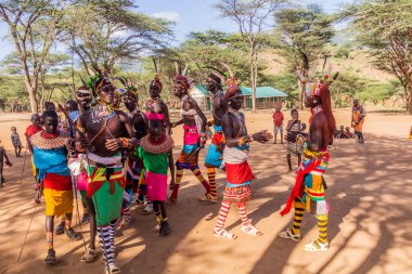 GÜNEY HORR, KENYA - 12 Şubat 2020: Samburu kabilesinden genç erkekler ve kadınlar malecircumsion seremonisinden sonra devekuşu tüylerinden yapılmış renkli başlıklar takarak dans ediyorlar.