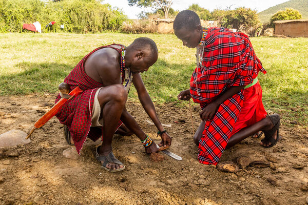 MASAI MARA, KENYA - FEBRUARY 20, 2020: Masai men making a fire in their village, Kenya